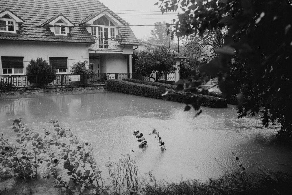 Black and white image of a suburban house affected by flooding during heavy rain